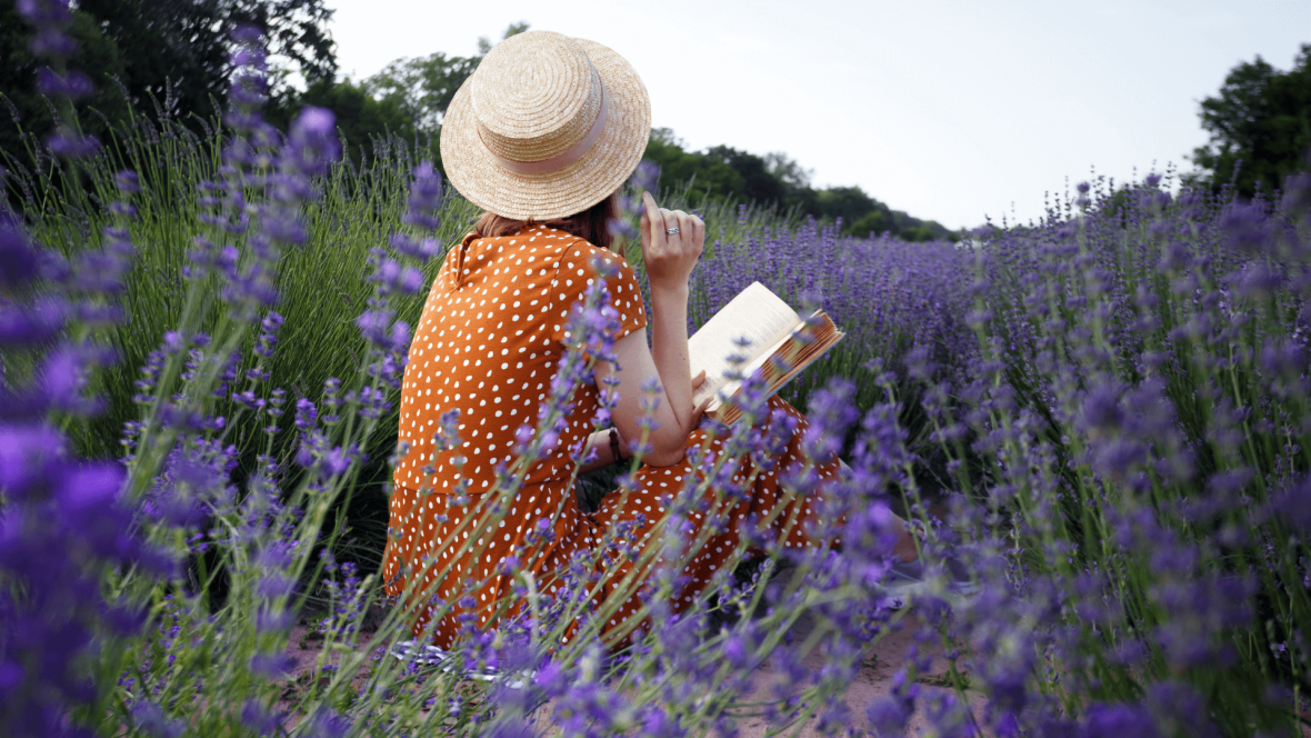 a girl with a book is sitting in a lavender field